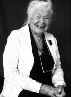 A black-and-white portrait of Ida Rolf, seated and smiling.