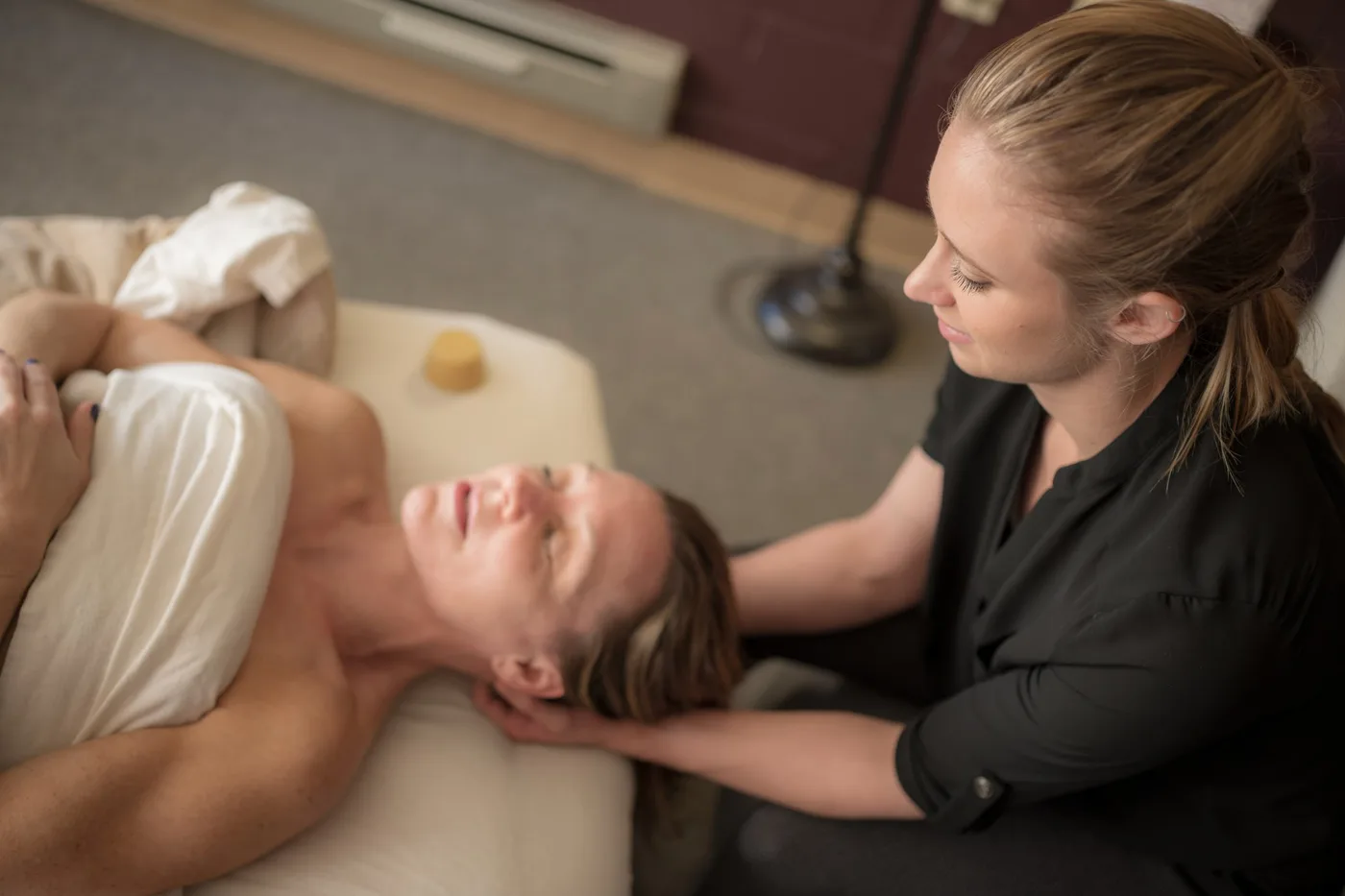 Katie cradling a client’s head and neck at the top of the treatment table.